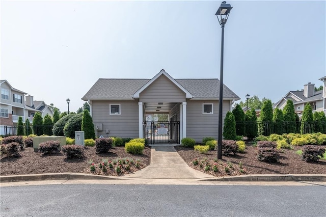 view of front of house featuring a shingled roof, a gate, and fence