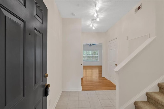 foyer with light tile patterned floors, baseboards, stairway, rail lighting, and a textured ceiling