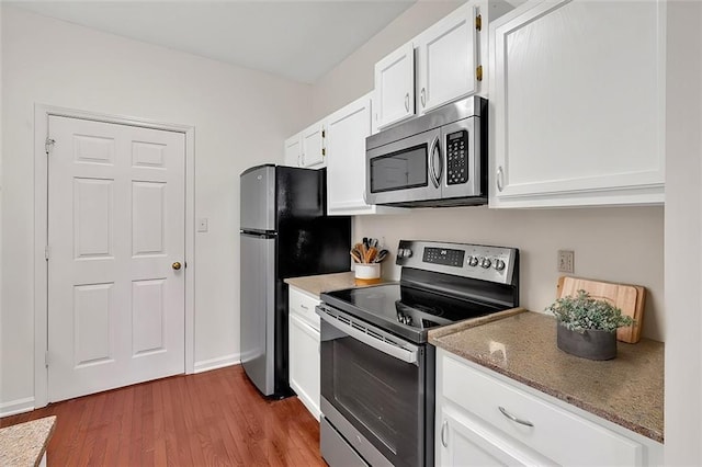 kitchen with stainless steel appliances, white cabinets, baseboards, and wood finished floors