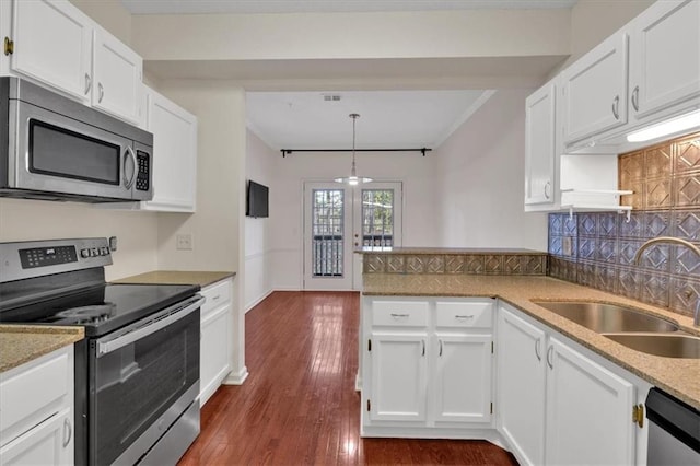 kitchen featuring a peninsula, a sink, white cabinetry, appliances with stainless steel finishes, and decorative backsplash