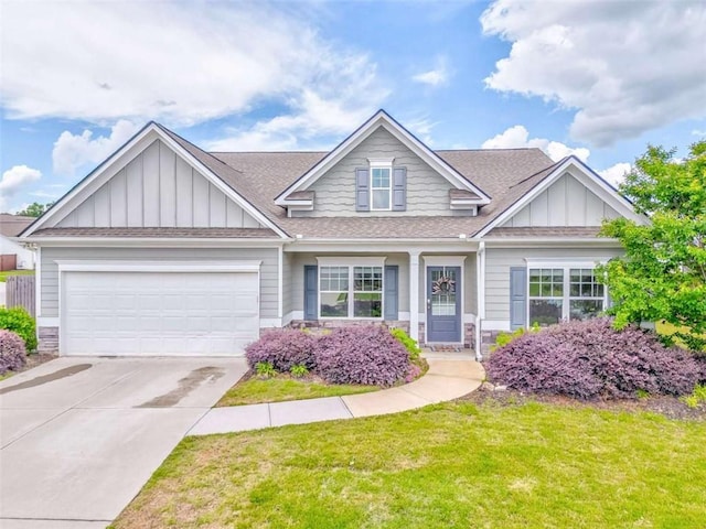 view of front facade with board and batten siding, roof with shingles, an attached garage, a front yard, and driveway