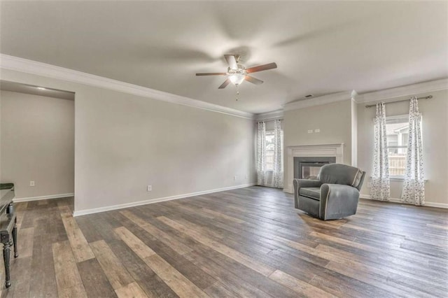 unfurnished living room featuring a ceiling fan, dark wood-style flooring, a glass covered fireplace, crown molding, and baseboards