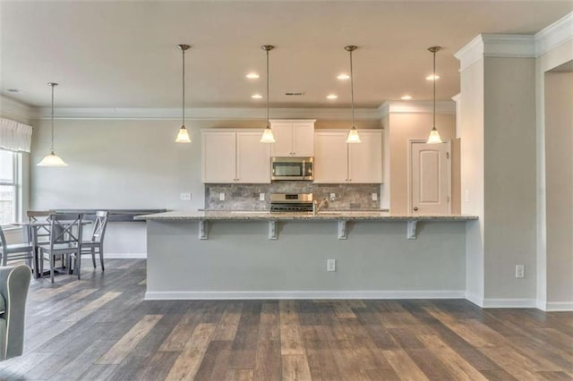 kitchen featuring appliances with stainless steel finishes, dark wood-type flooring, tasteful backsplash, white cabinetry, and crown molding