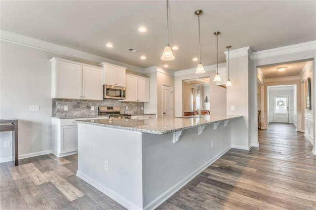 kitchen featuring appliances with stainless steel finishes, ornamental molding, white cabinets, a peninsula, and tasteful backsplash
