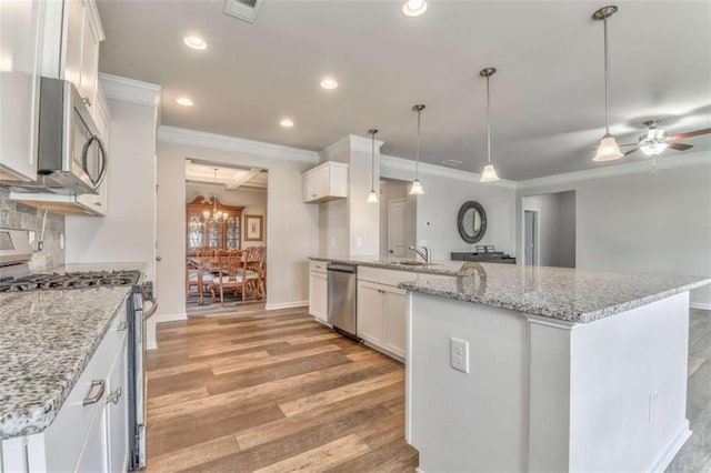 kitchen featuring stainless steel appliances, ornamental molding, light wood-type flooring, white cabinets, and a sink
