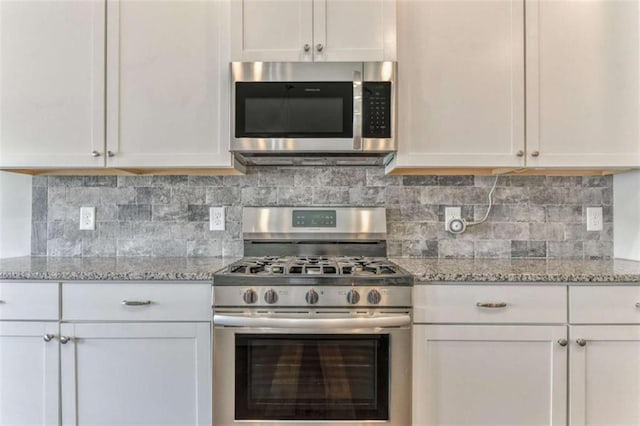 kitchen featuring appliances with stainless steel finishes, white cabinetry, backsplash, and light stone countertops
