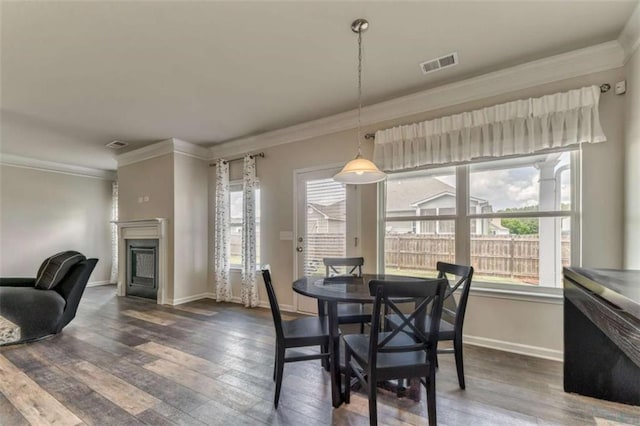 dining room with crown molding, a fireplace, wood finished floors, and baseboards