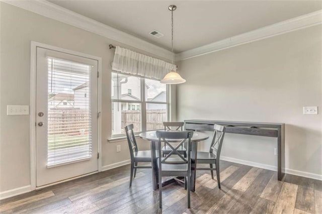 dining space with ornamental molding, wood finished floors, and baseboards