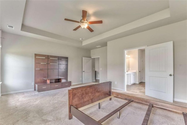 unfurnished office featuring a tray ceiling, ceiling fan, baseboards, and light colored carpet