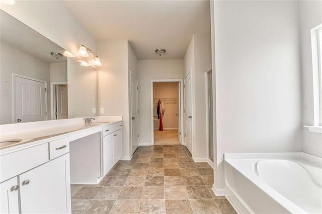 full bath featuring double vanity, a garden tub, baseboards, a walk in closet, and a shower stall