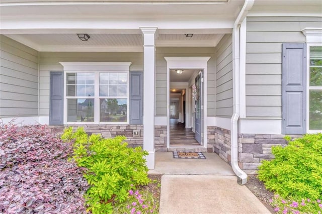 view of exterior entry featuring stone siding and covered porch