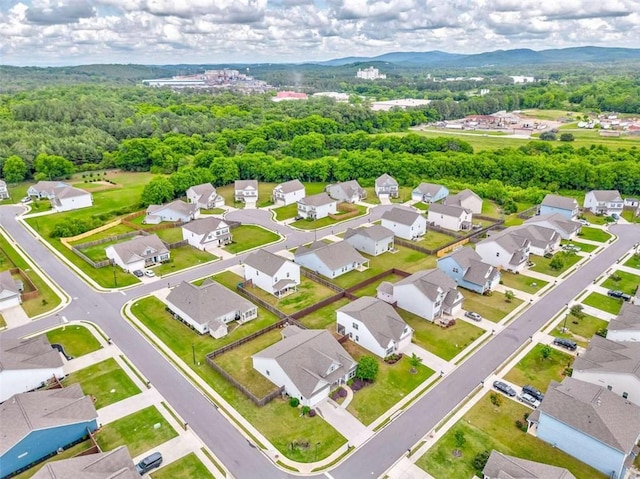 aerial perspective of suburban area featuring a mountain backdrop and a heavily wooded area