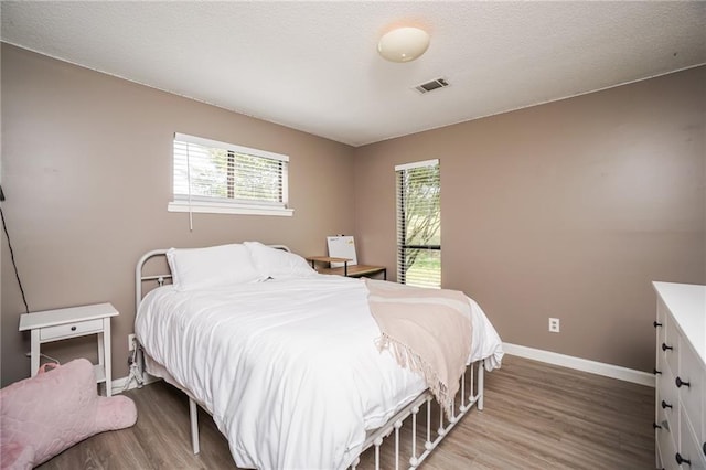 bedroom with hardwood / wood-style flooring and multiple windows