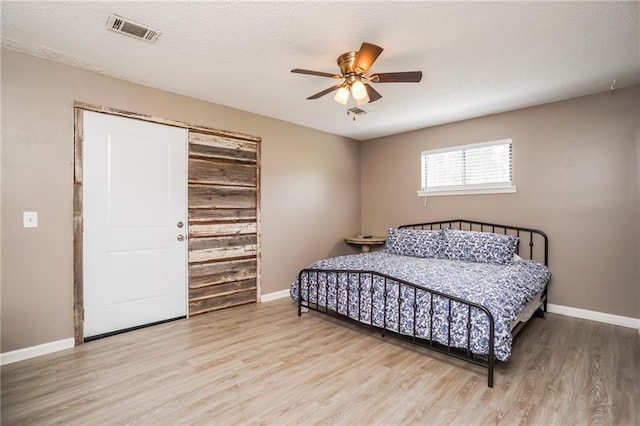 bedroom with ceiling fan, light hardwood / wood-style flooring, and a textured ceiling