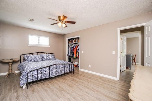 bedroom featuring ceiling fan, a closet, a textured ceiling, and light wood-type flooring