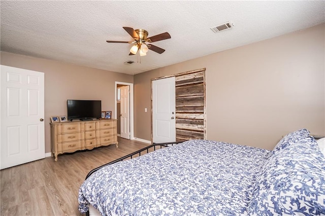 bedroom with light wood-type flooring, a textured ceiling, a closet, and ceiling fan