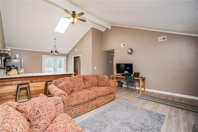 living room with french doors, light wood-type flooring, a skylight, ceiling fan, and beamed ceiling