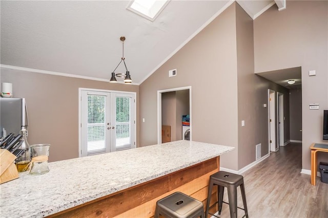 kitchen featuring french doors, hanging light fixtures, crown molding, hardwood / wood-style floors, and a kitchen bar