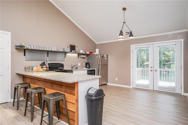 kitchen featuring stainless steel refrigerator, black stove, hanging light fixtures, kitchen peninsula, and a breakfast bar area