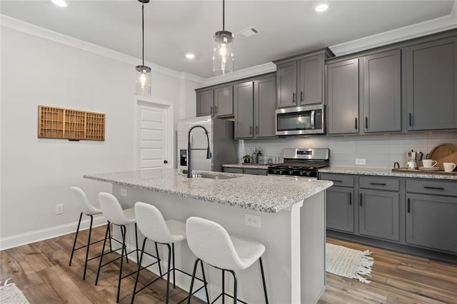 141 Wingate Dr, Auburn, GA 30680 - kitchen with appliances with stainless steel finishes, crown molding, a kitchen island with sink, a breakfast bar area, and decorative backsplash