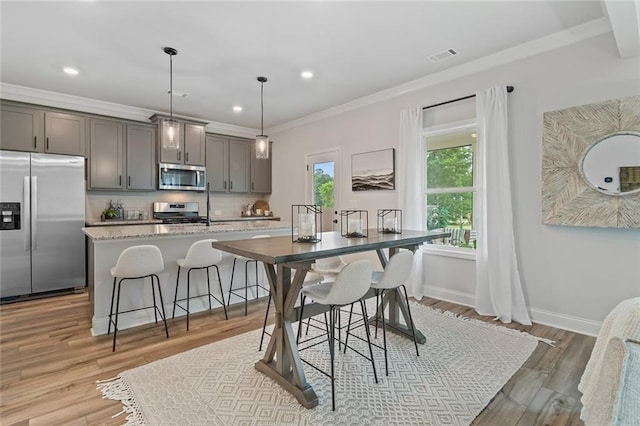 141 Wingate Dr, Auburn, GA 30680 - kitchen with appliances with stainless steel finishes, crown molding, tasteful backsplash, a center island with sink, and light wood-style flooring