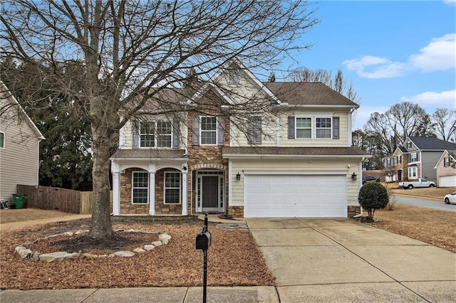 traditional-style home featuring an attached garage, a shingled roof, fence, stone siding, and concrete driveway