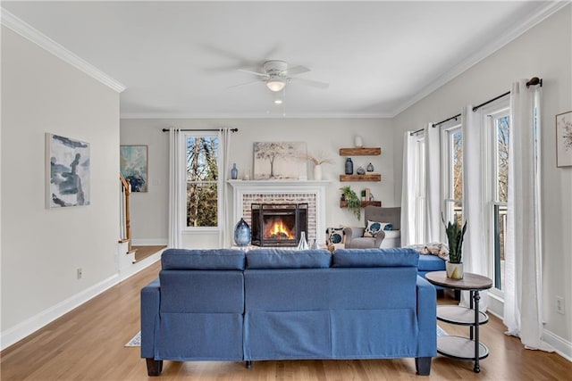 living room with crown molding, ceiling fan, wood-type flooring, and a fireplace