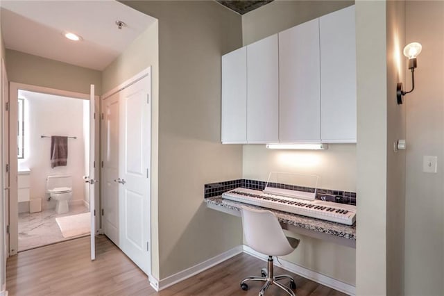 home office featuring light wood-type flooring and built in desk