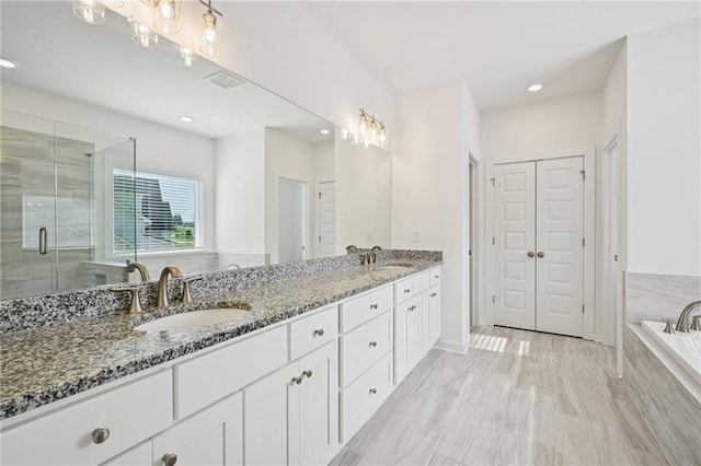 8125 Beryl Overlook, Gainesville, GA 30506 - full bathroom featuring tiled tub, double vanity, recessed lighting, a stall shower, and a closet