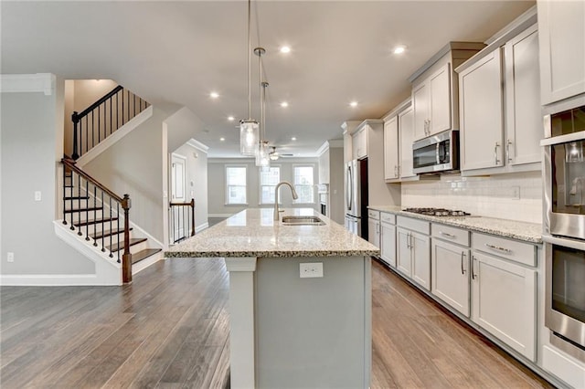 4232 Perimeter Park E Unit 110, Atlanta, GA 30341 - kitchen with appliances with stainless steel finishes, wood finished floors, a center island with sink, tasteful backsplash, and crown molding