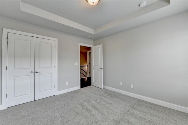 4232 Perimeter Park E Unit 110, Atlanta, GA 30341 - unfurnished bedroom featuring a tray ceiling, carpet, and a closet