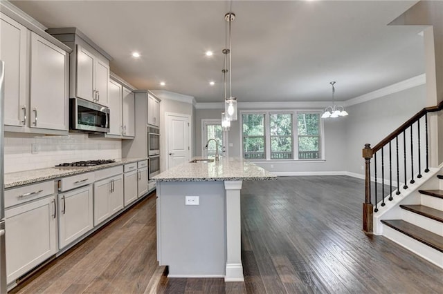 4232 Perimeter Park E Unit 110, Atlanta, GA 30341 - kitchen with appliances with stainless steel finishes, crown molding, tasteful backsplash, dark wood-type flooring, and an island with sink