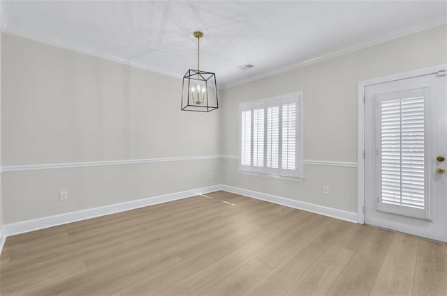 spare room featuring light wood-type flooring, a chandelier, and crown molding