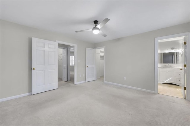 unfurnished bedroom featuring a walk in closet, sink, a closet, light carpet, and ensuite bathroom