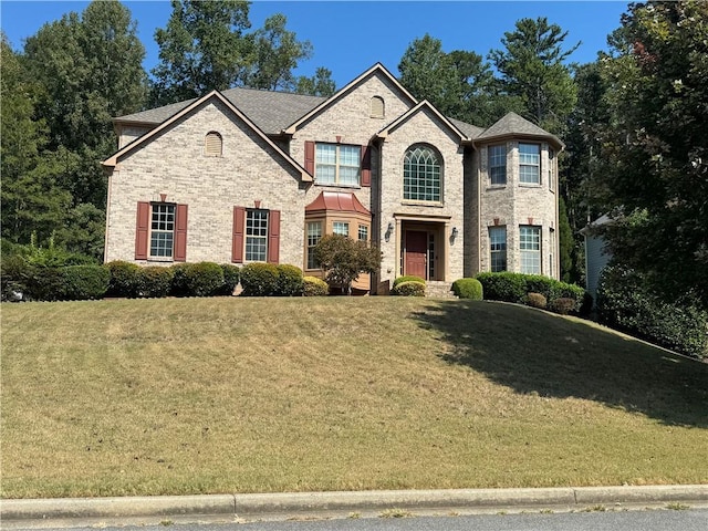 french provincial home with a front lawn and brick siding