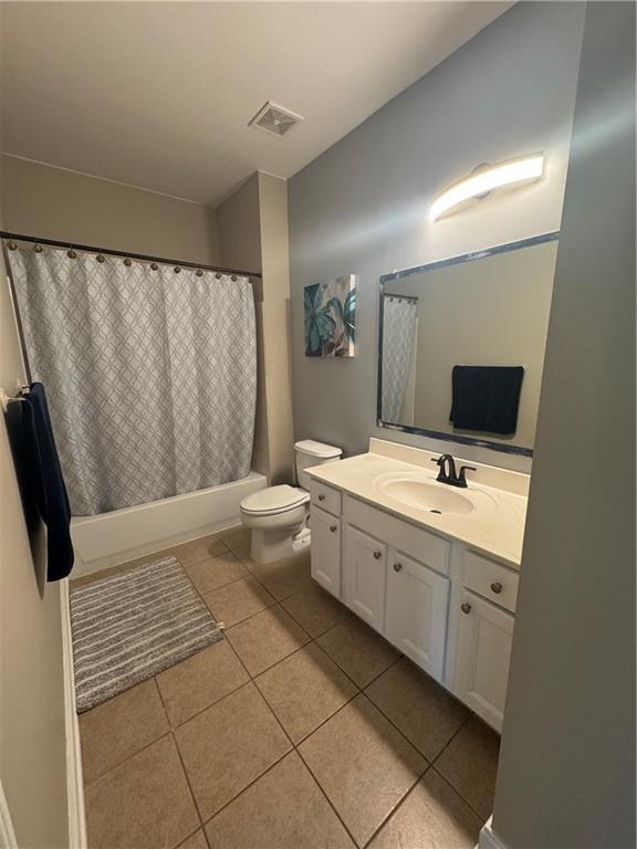 full bath with toilet, vanity, tile patterned flooring, shower / bath combo with shower curtain, and visible vents