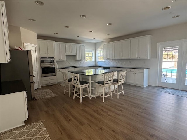 kitchen with white cabinetry, a breakfast bar area, dark countertops, and a sink