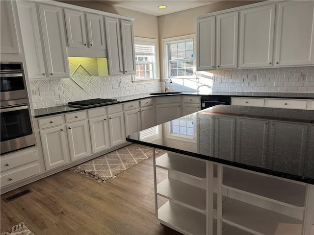 kitchen featuring visible vents, wood finished floors, dark stone countertops, double oven, and stovetop