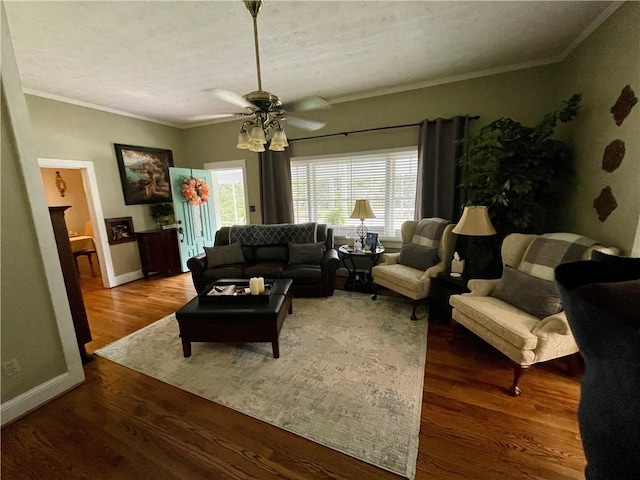 living room featuring wood-type flooring, a textured ceiling, ornamental molding, and ceiling fan