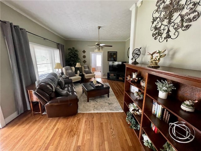 living room with a textured ceiling, crown molding, light hardwood / wood-style floors, and ceiling fan