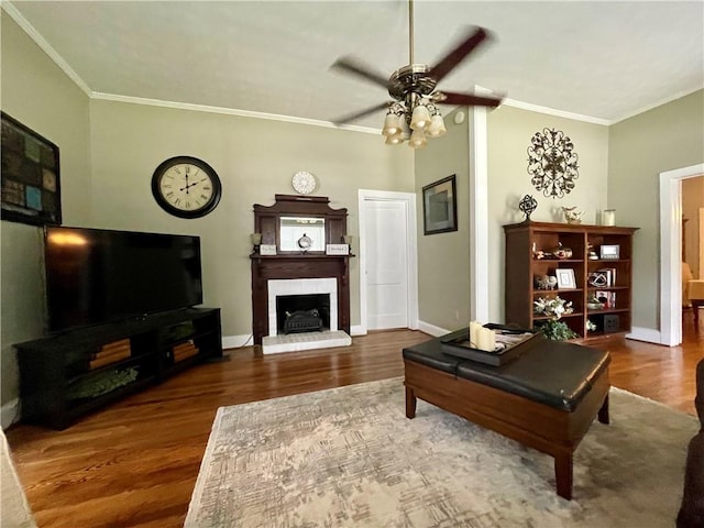 living room with a brick fireplace, ceiling fan, hardwood / wood-style floors, and crown molding