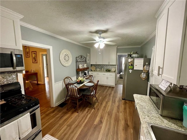 kitchen with white cabinetry, stainless steel appliances, a textured ceiling, crown molding, and hardwood / wood-style flooring