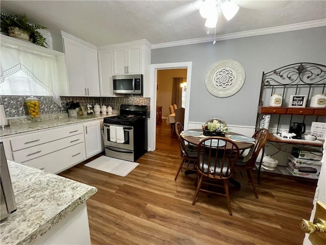 kitchen with stainless steel appliances, white cabinetry, and dark wood-type flooring