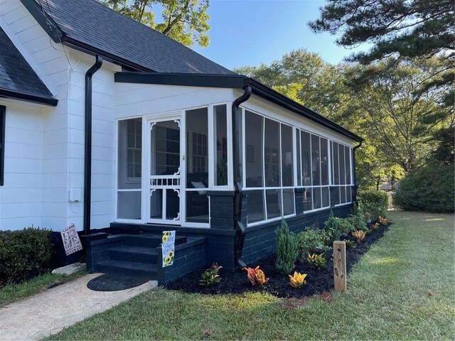 view of side of home with a sunroom and a lawn