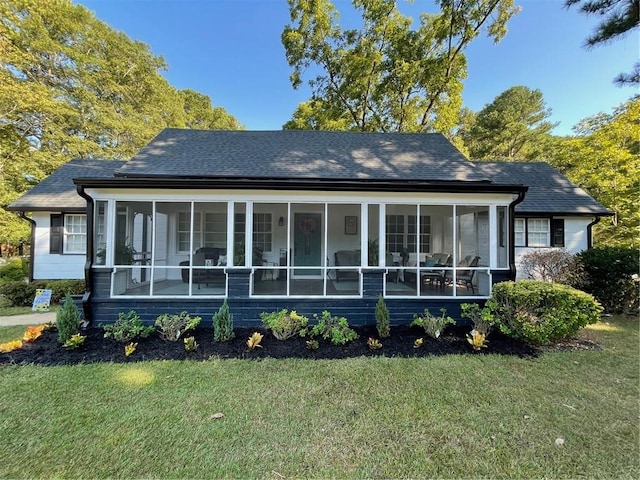 rear view of house featuring a lawn and a sunroom