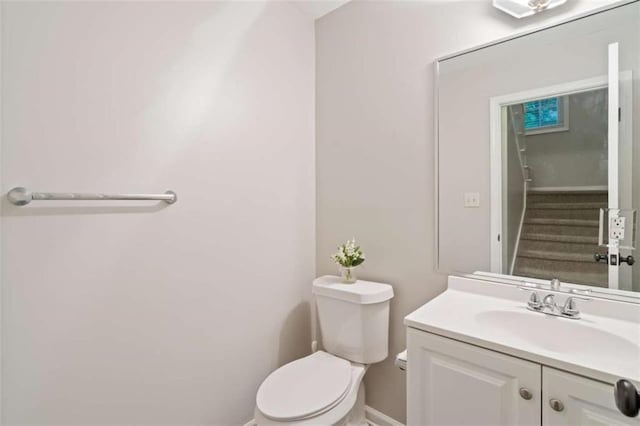 half bath with vanity, toilet, and baseboards