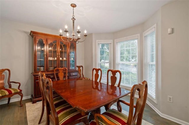 dining space featuring dark wood-style floors, baseboards, and an inviting chandelier