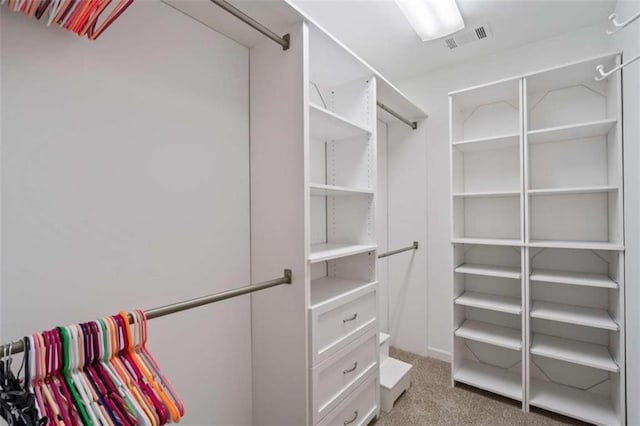 walk in closet featuring visible vents and light carpet