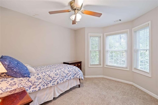 carpeted bedroom featuring baseboards, visible vents, and ceiling fan