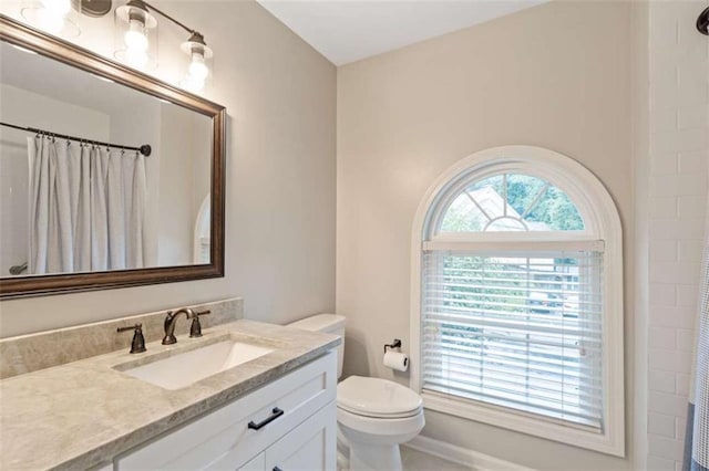 bathroom with toilet, plenty of natural light, vanity, and a shower with curtain